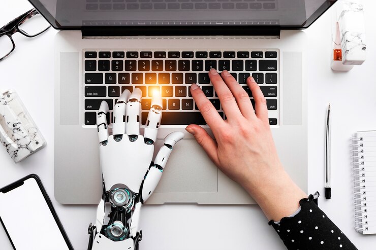 Mão de robô representando a IA auxiliando uma mão humana a usar o computador, representando o mercado de trabalho.